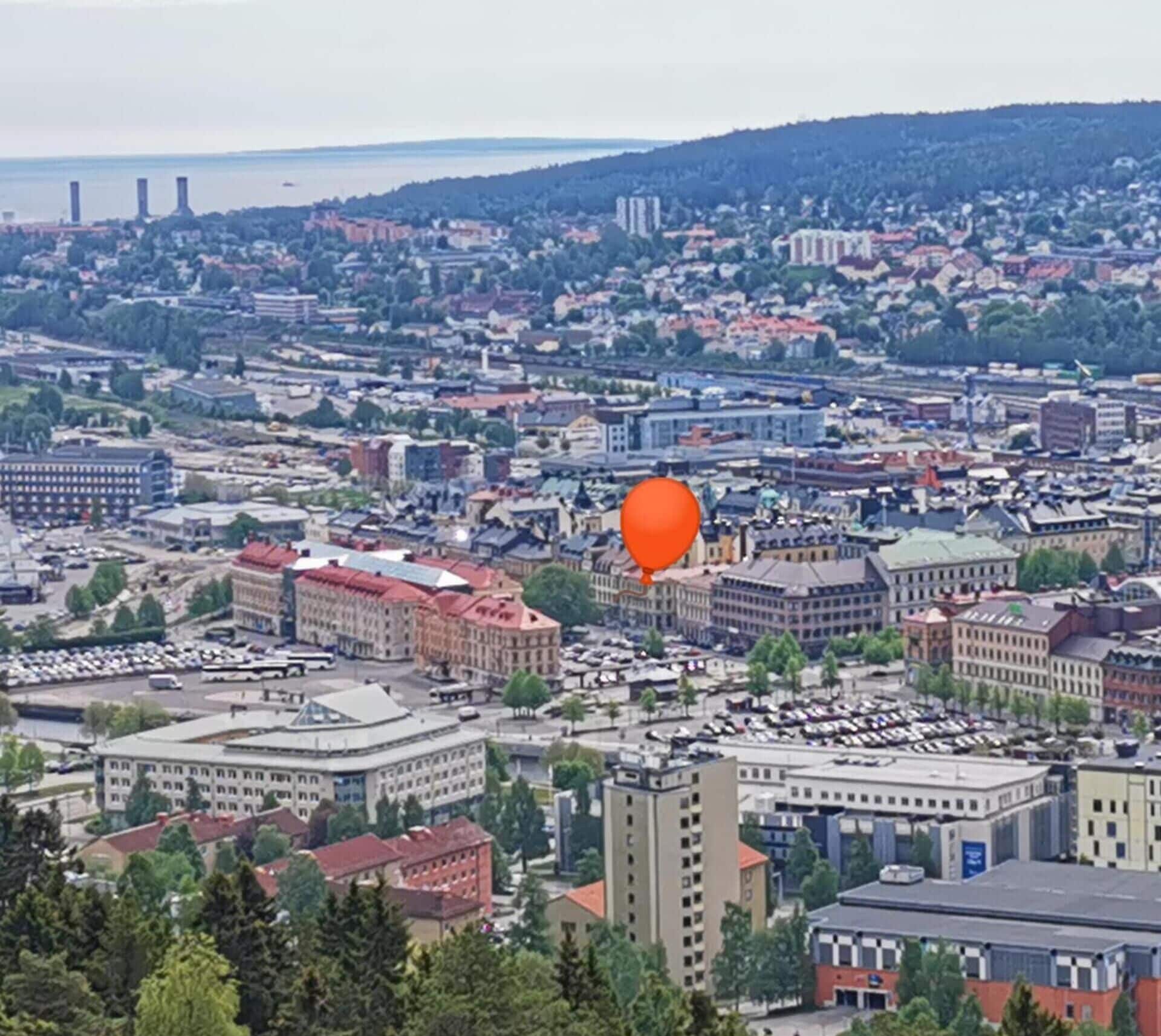 Un paisaje urbano con diversos edificios, incluyendo un edificio destacado de techo rojo en primer plano.