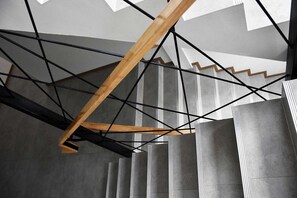 A modern interior with a geometric ceiling design, concrete pillars, and exposed wooden beams. - Tuck Me iN (Chiang Mai)