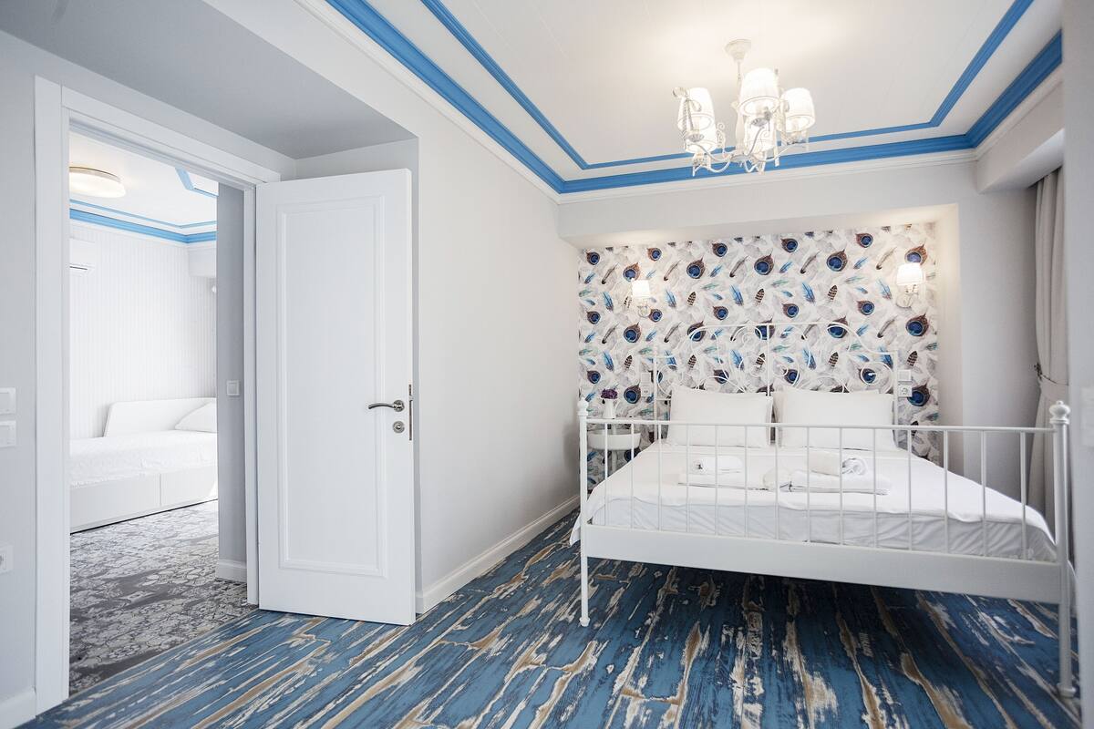 A bedroom with a white bed, a patterned headboard, and a blue and white floor.