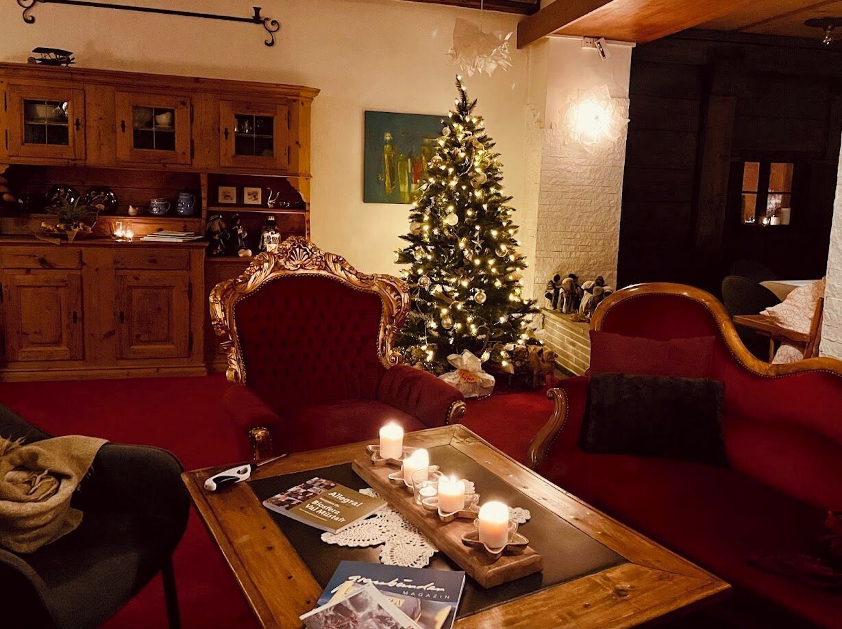 Una sala de estar acogedora con un sofá rojo, una mesa de centro de madera con velas y un árbol de Navidad.