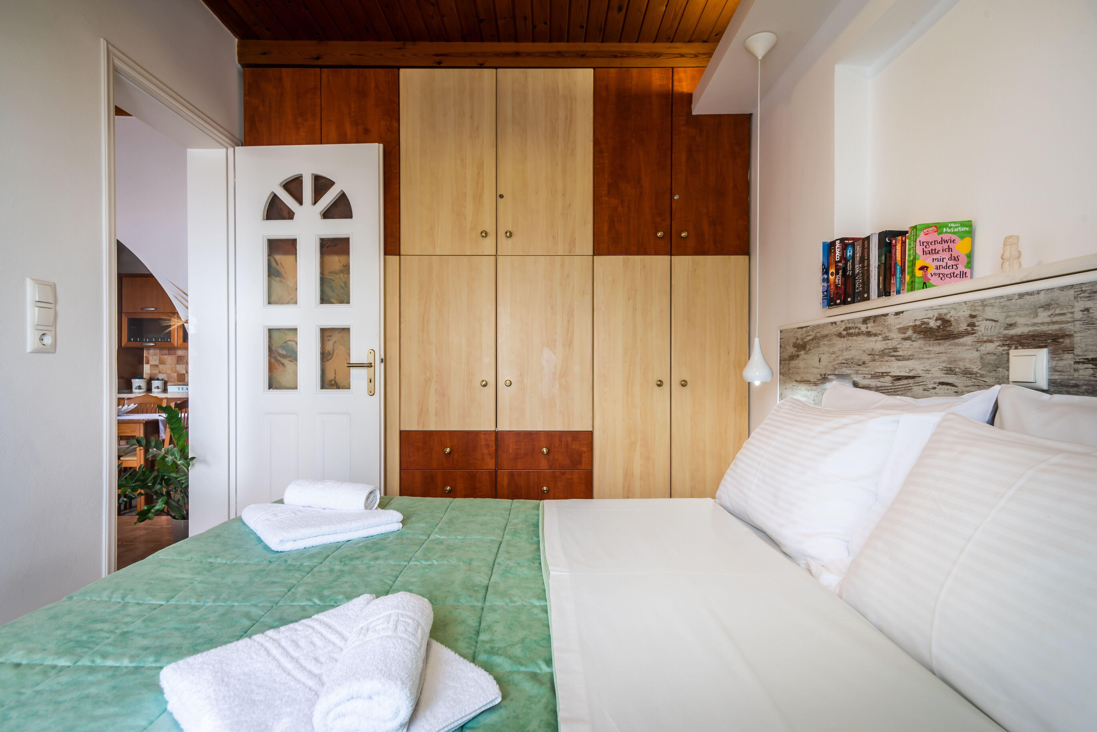 A bedroom with a bed, a wardrobe, and a shelf with books.
