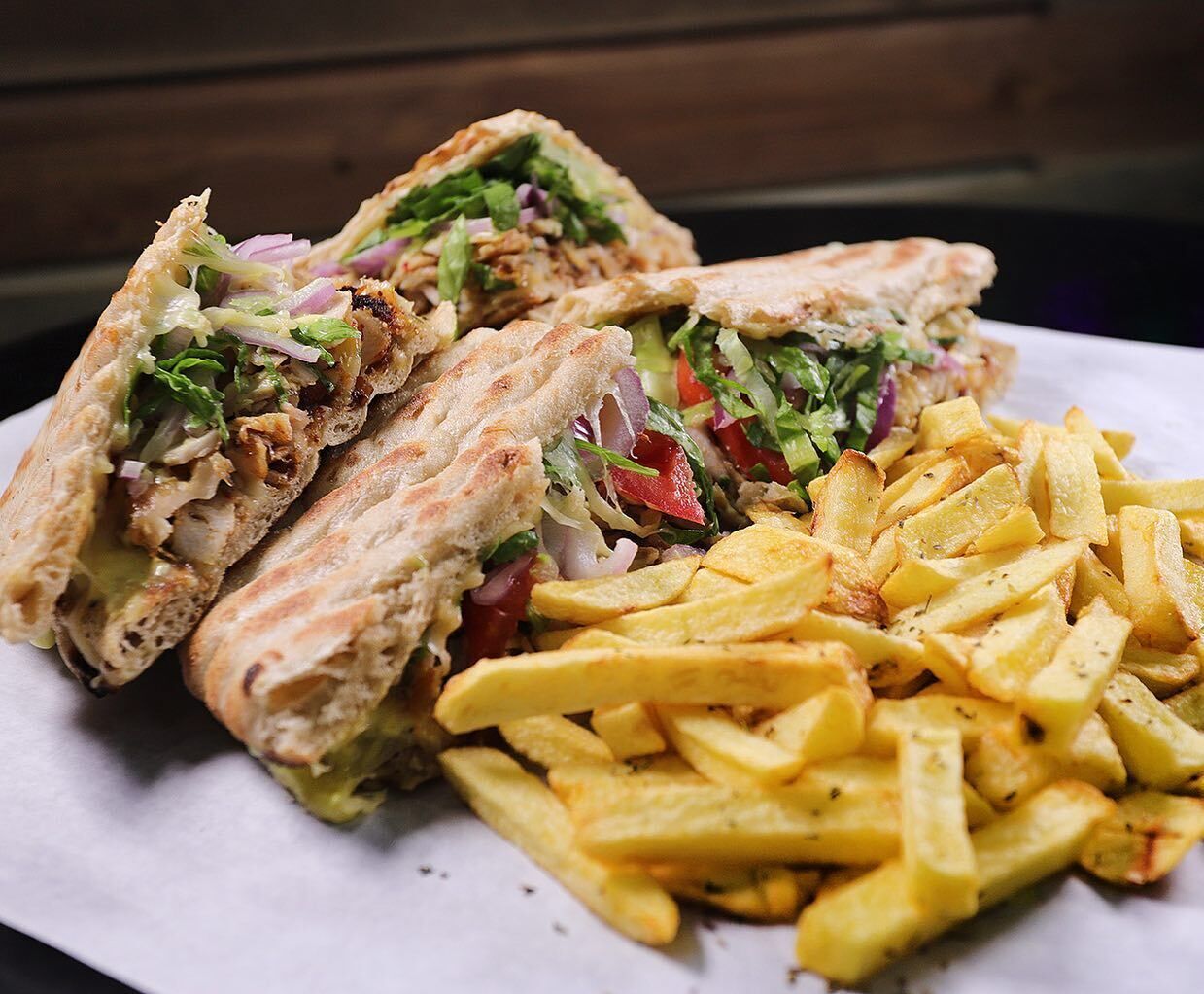 A sandwich cut in half with fries on a white plate.
