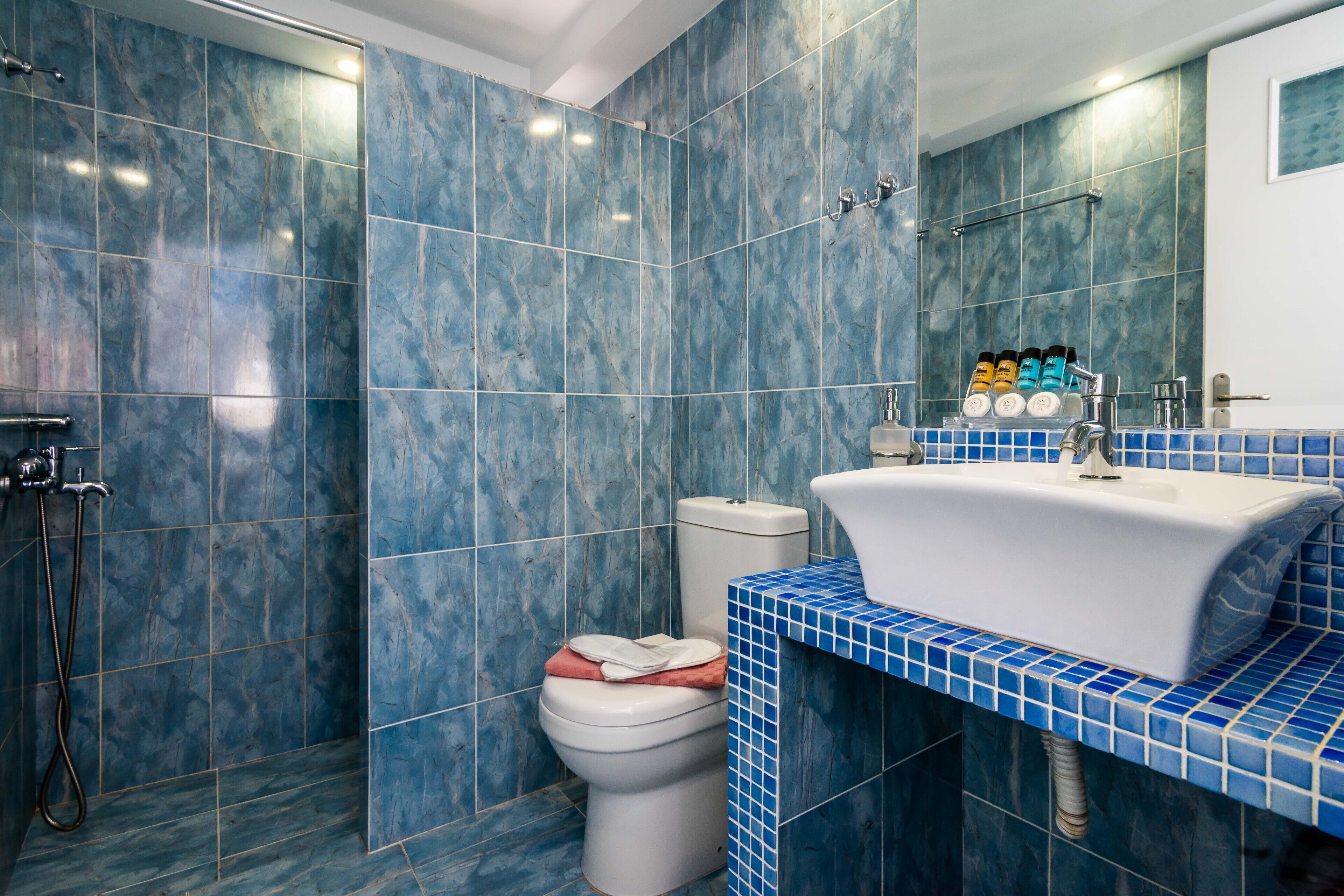 Een badkamer met blauwe marmeren tegels, een wit wastafelmeubel en een toilet.