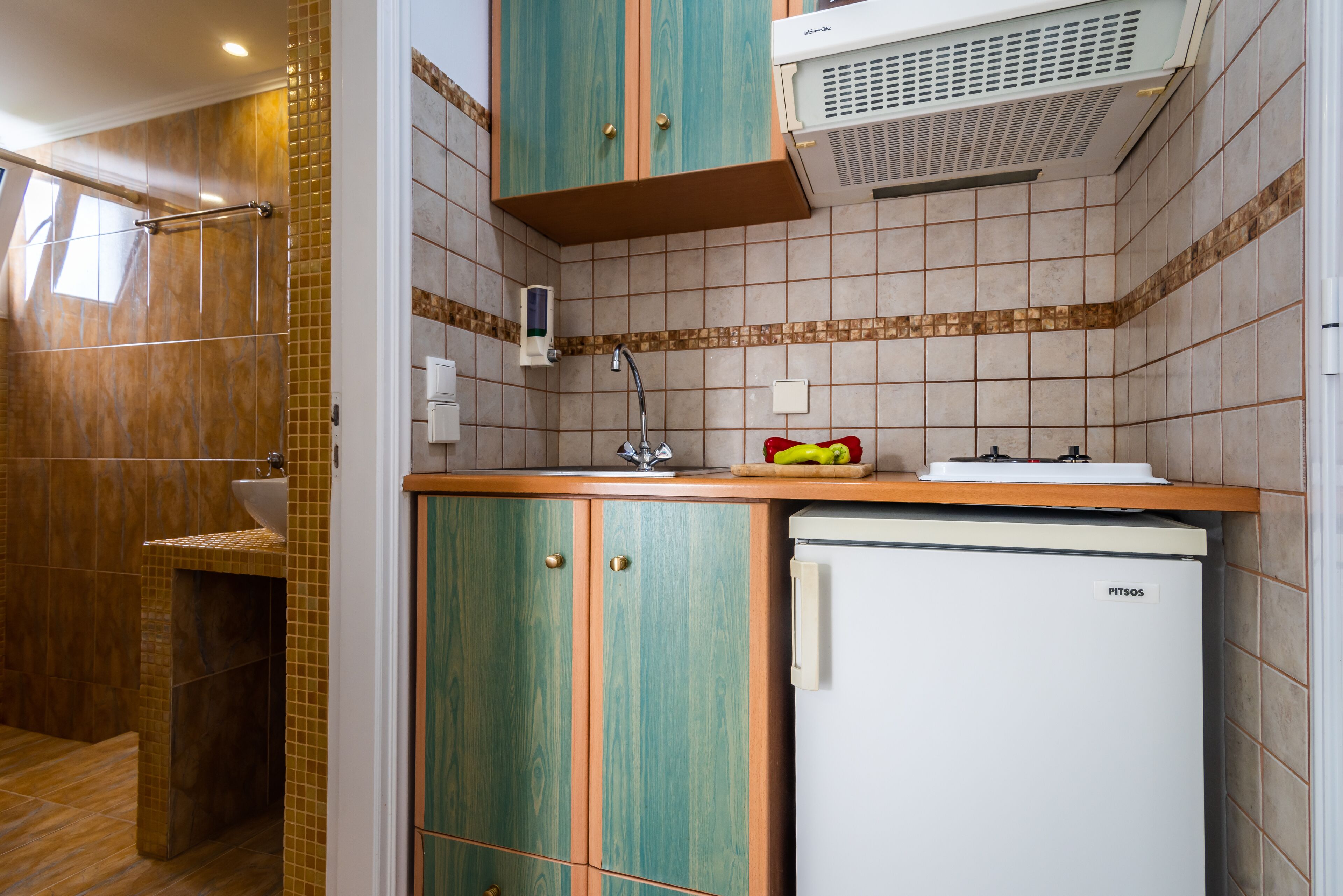 A compact kitchen with a refrigerator, a sink, and a window.