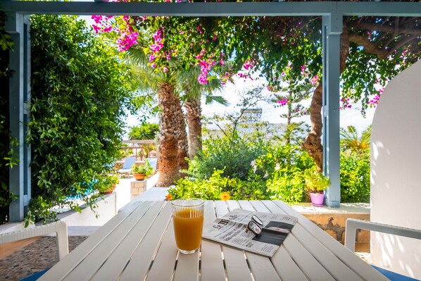 A white table with a glass of orange juice, a newspaper, and a smartphone. - Orizontes Studios (Milos)