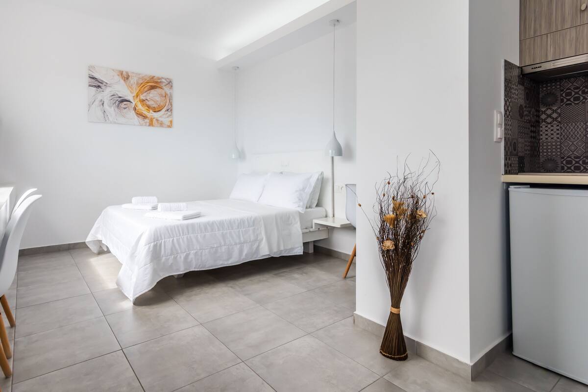 A modern, minimalist bedroom with a bed, bedside table, and a decorative vase.
