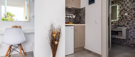Una cocina moderna con un armario blanco, un refrigerador pequeño y un salpicadero de azulejos.