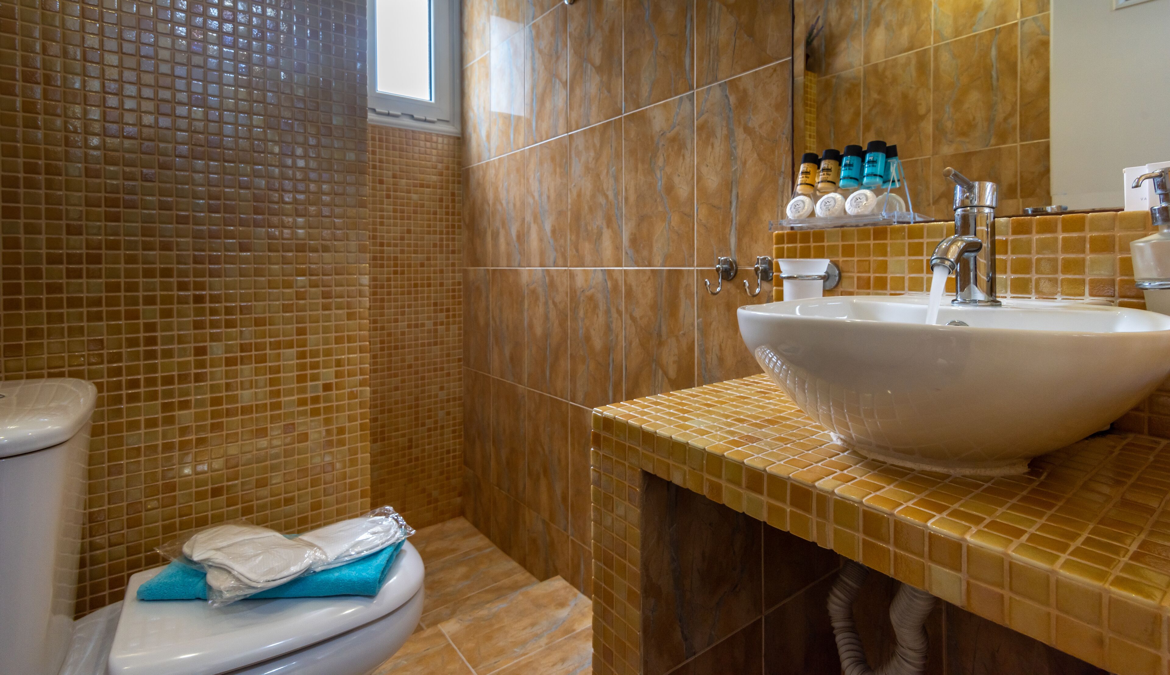 Casa de banho com sanita, lavatório e paredes com azulejos.