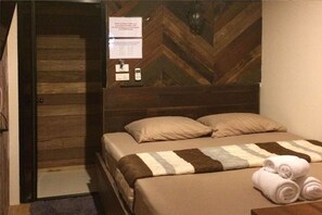 A hotel room with a wooden headboard, a bed with beige bedding, and a sign with check-in instructions. - Mojo House (Chiang Mai)