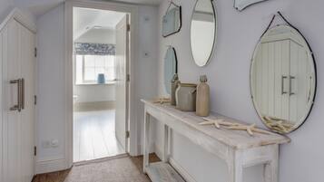 A hallway with a white door, a white console table with jars, and a mirror.