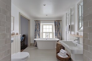 A modern bathroom with a freestanding bathtub, a large mirror, and a white sink.