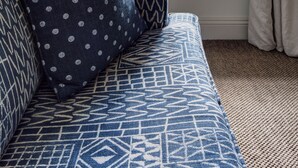 A room with a window seat, a patterned sofa, and a view of the sea. - The Idle Rocks (Truro)
