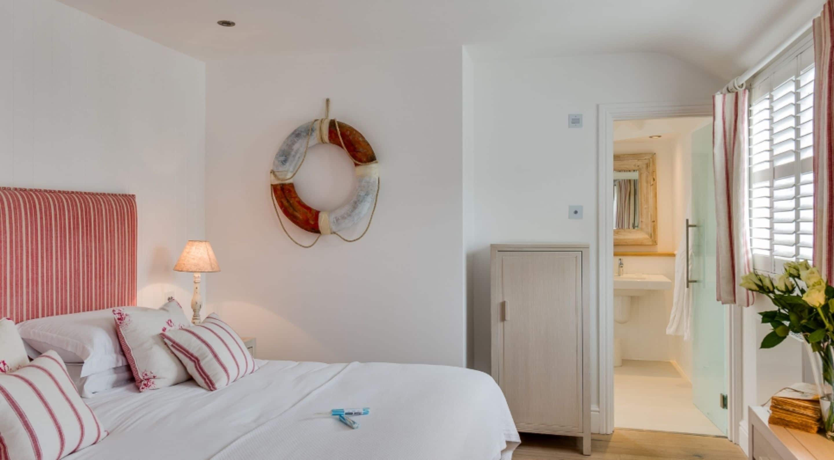 A bedroom with a bed, a bedside lamp, a wall-mounted circular decoration, and a view into the bathroom.