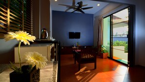 Una sala moderna con ventilador de techo, televisor de pantalla plana, zona de comedor con mesa y sillas, y un gran ventanal corredizo que da a un balcón.