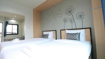Habitación de hotel con dos camas, un ventanal grande y un adorno de diente de león en la pared.