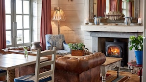 A cozy living room with a fireplace, leather furniture, and a patterned armchair. - St Mawes Hotel (Truro)