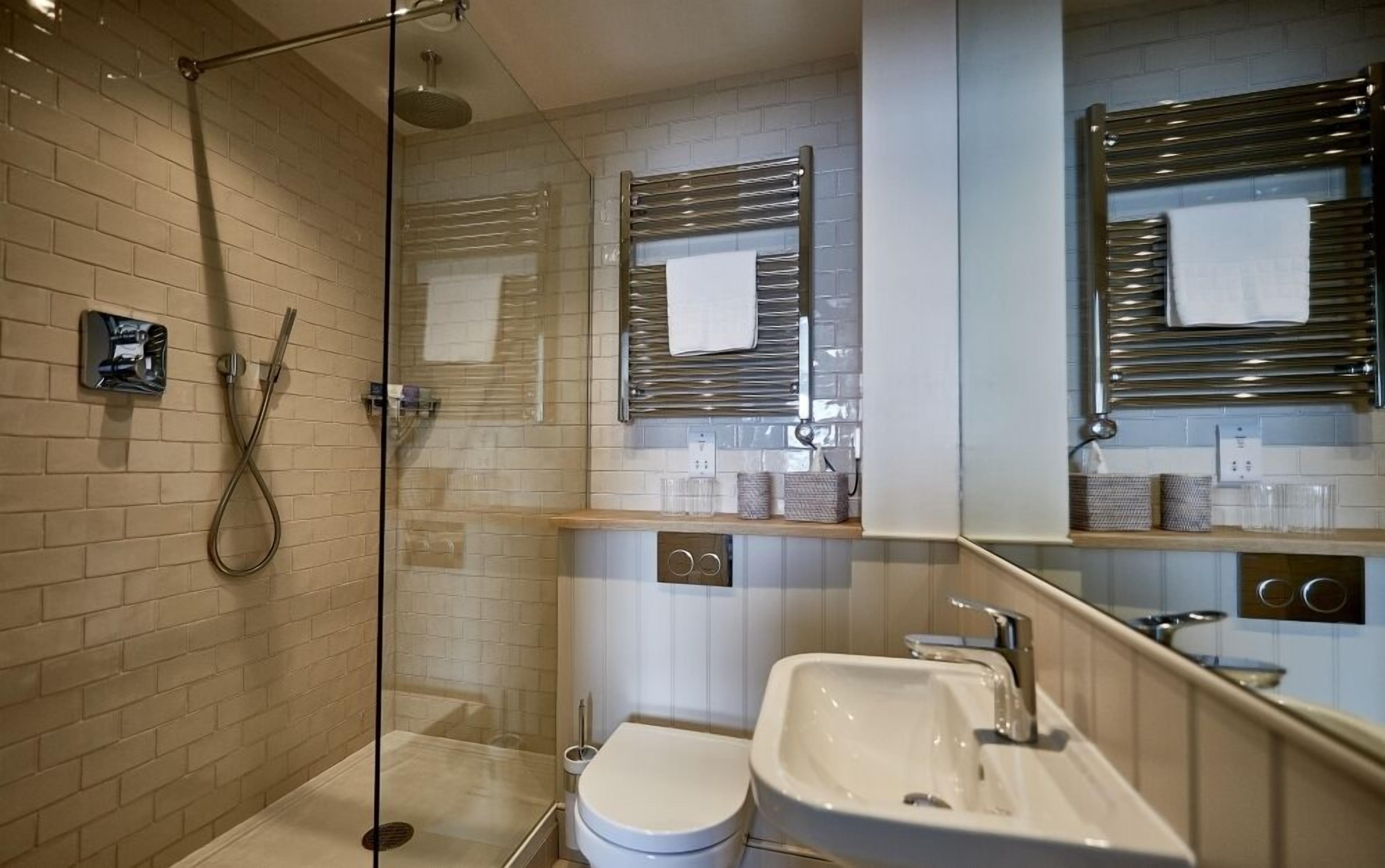 A modern bathroom with a glass-enclosed shower, a white toilet, and a sink with a mirror above it.