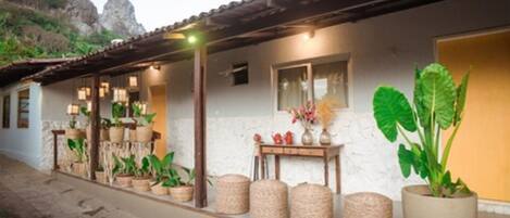 A rustic building with a tiled roof, potted plants, and a small table with decorative items.