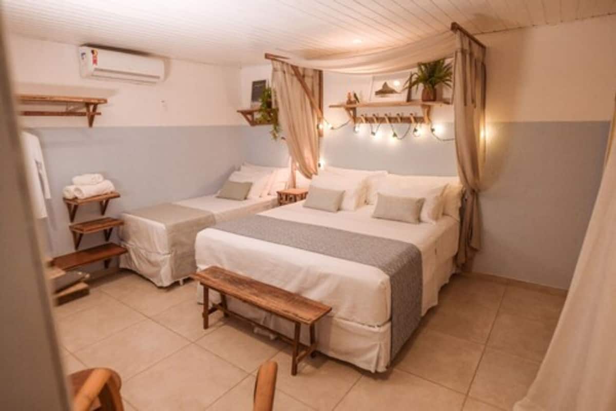 Ein Schlafzimmer mit zwei Betten, einer Bank, einem Schreibtisch und einer hängenden Pflanze.
