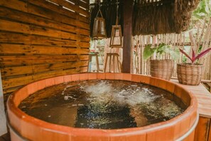Ein Whirlpool mit einer Holzwand und einem Reetdach im Hintergrund.