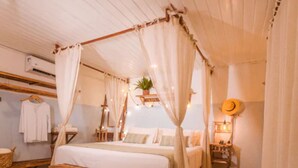 Une chambre confortable avec un lit à baldaquin, un banc, une plante suspendue et un chapeau accroché au mur.