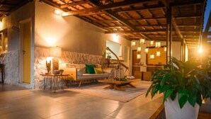 Un salon chaleureux avec un mur en pierre, un plafond en bois et un canapé agrémenté de coussins.