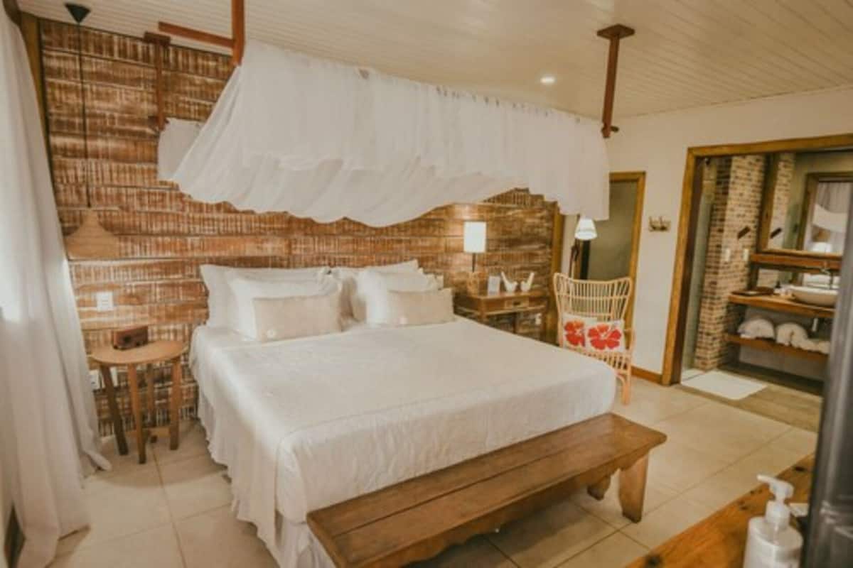 Ein Schlafzimmer mit einem hölzernen Bett, einer Bank, einem Stuhl, einem Nachttisch und einem Beistelltisch.