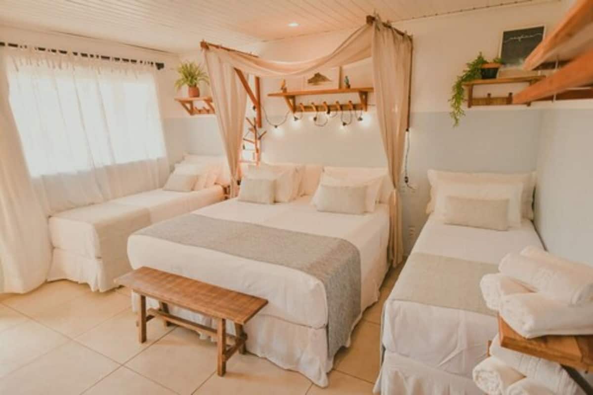 Ein Zimmer mit zwei Betten, einer Bank und einem Himmelbett. Pflanzen stehen auf Regalen, eine Leiter ist ebenfalls vorhanden.