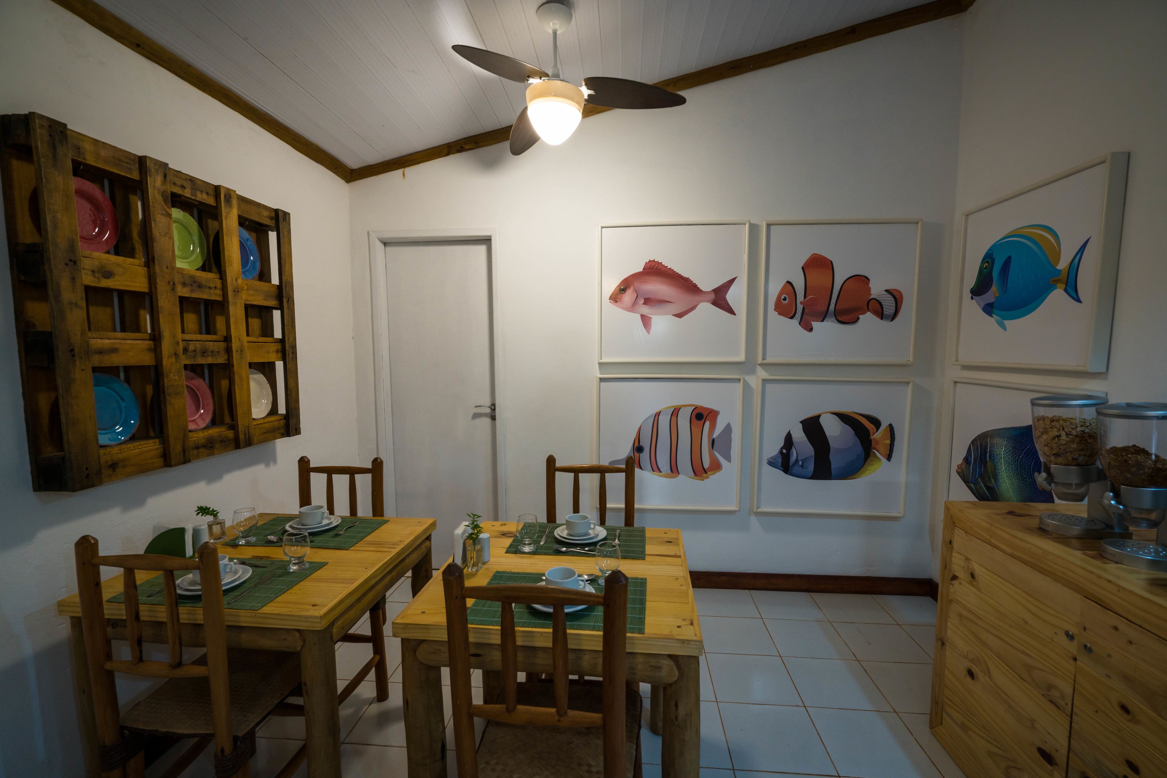A dining area with wooden tables and chairs, a ceiling fan, and fish-themed wall art.