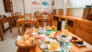 Ein Holztisch mit Frühstücksangeboten, darunter Brot, Obst und Kuchen.