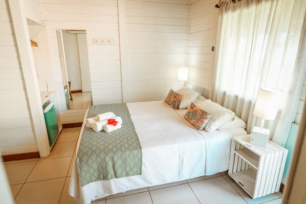 A neatly arranged bedroom with a bed, bedside table, and a mirror.
