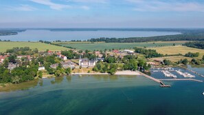 An aerial view of a lakeside town with a marina, residential buildings, and open fields. - Kells Appartements (Klink)
