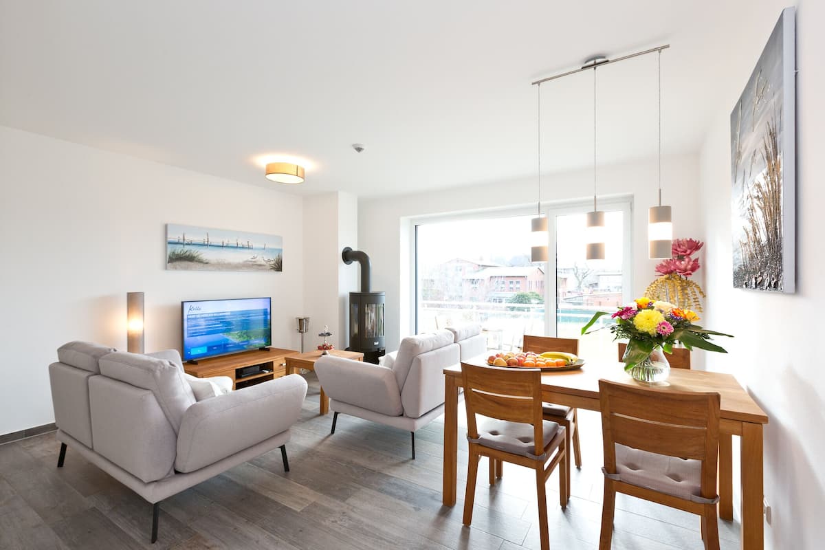 Ein modernes Wohnzimmer mit einer Couch, einem Fernseher, einem Esstisch, Stühlen und einem Kamin.