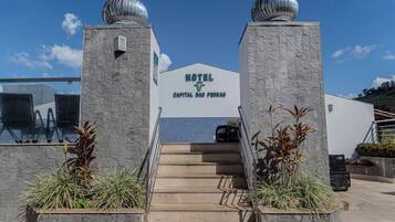 Entrada de um hotel com uma escadaria que leva a uma placa com a inscrição 'HOTEL CAPITAL DAS PEREAS'.