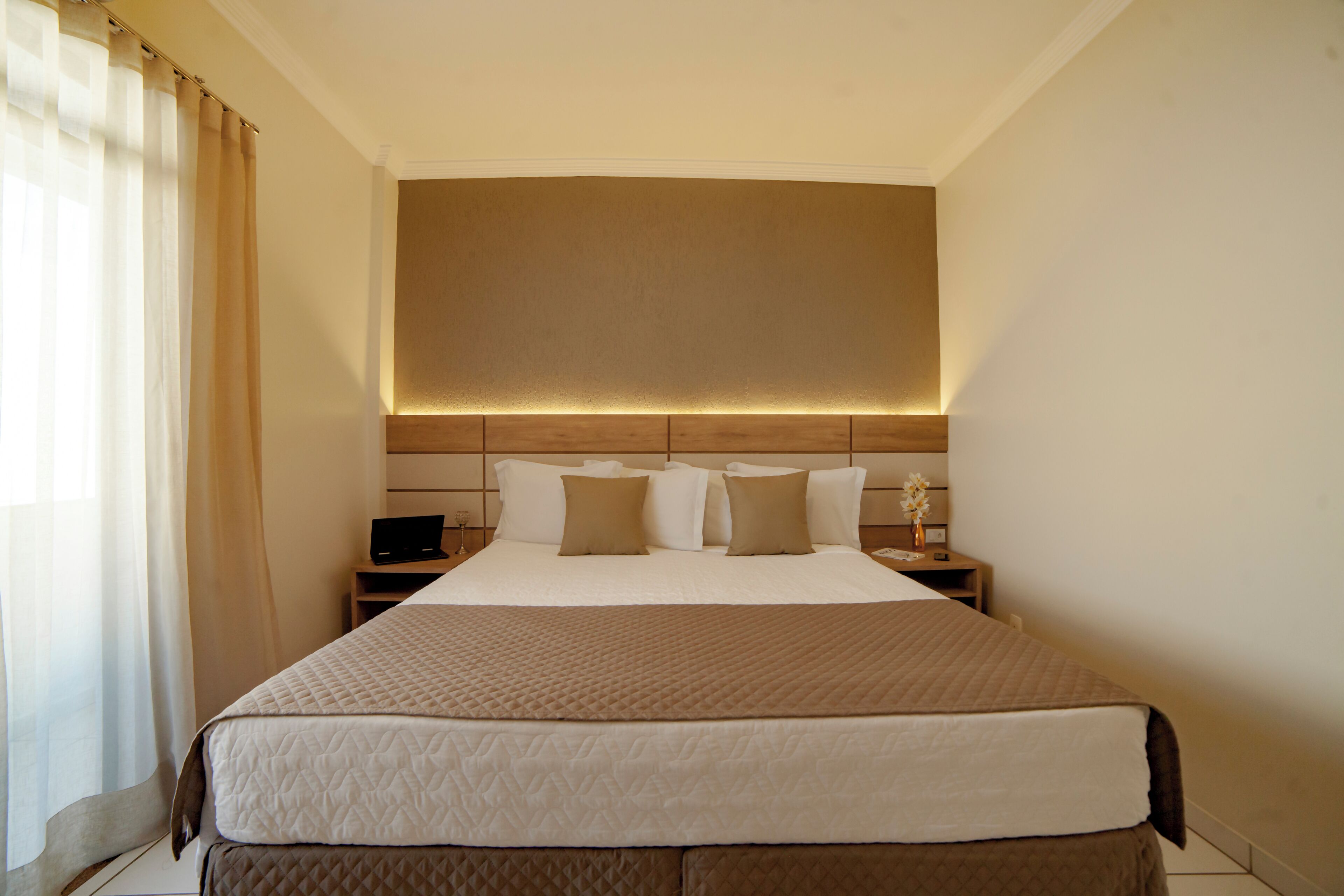 A hotel room with a large bed, a bedside table with a lamp, and a headboard with integrated lighting.