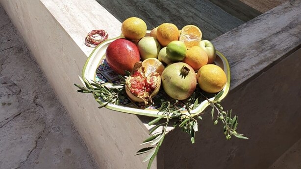 Un mur de pierre agrémenté d’un élément décoratif aquatique et d’un récipient rempli de fruits et d’herbes aromatiques.