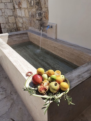A stone wall with a water feature and a bowl of fruits and herbs. - SPITI Calliope - ex House of Eleni (Kathikas)
