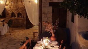 Un espace de restauration en plein air avec des murs en pierre, une table dressée pour deux personnes et une atmosphère rustique.