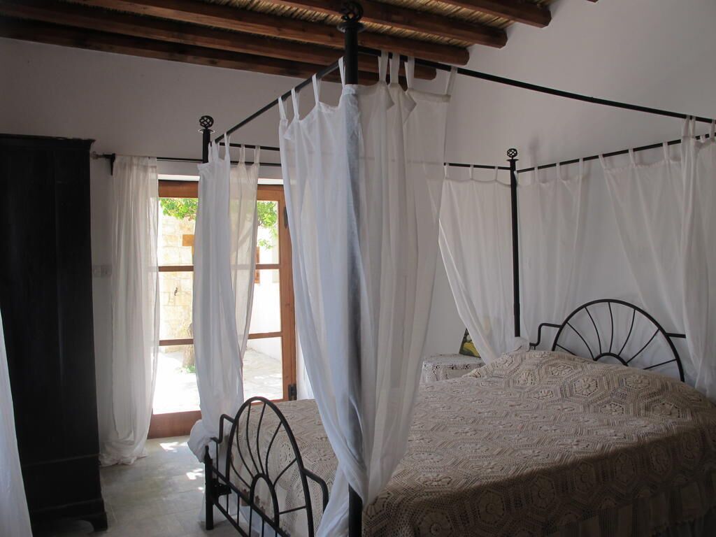 Una habitación con cama, una silla y una ventana con cortinas.