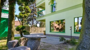 A building with a green facade, a balcony with yellow flowers, and a paved courtyard with stone seating. - Hotel Zielony (Poznan)