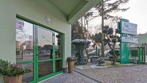A hotel entrance with a green door, a signboard, and a potted plant. - Hotel Zielony (Poznan)