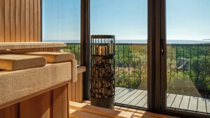 A wooden bench area with a view of the ocean through large windows. - Hotel Alaia (Pichilemu)