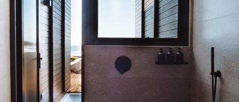 A modern bathroom with a large window, a shower area, and a visible outdoor view.