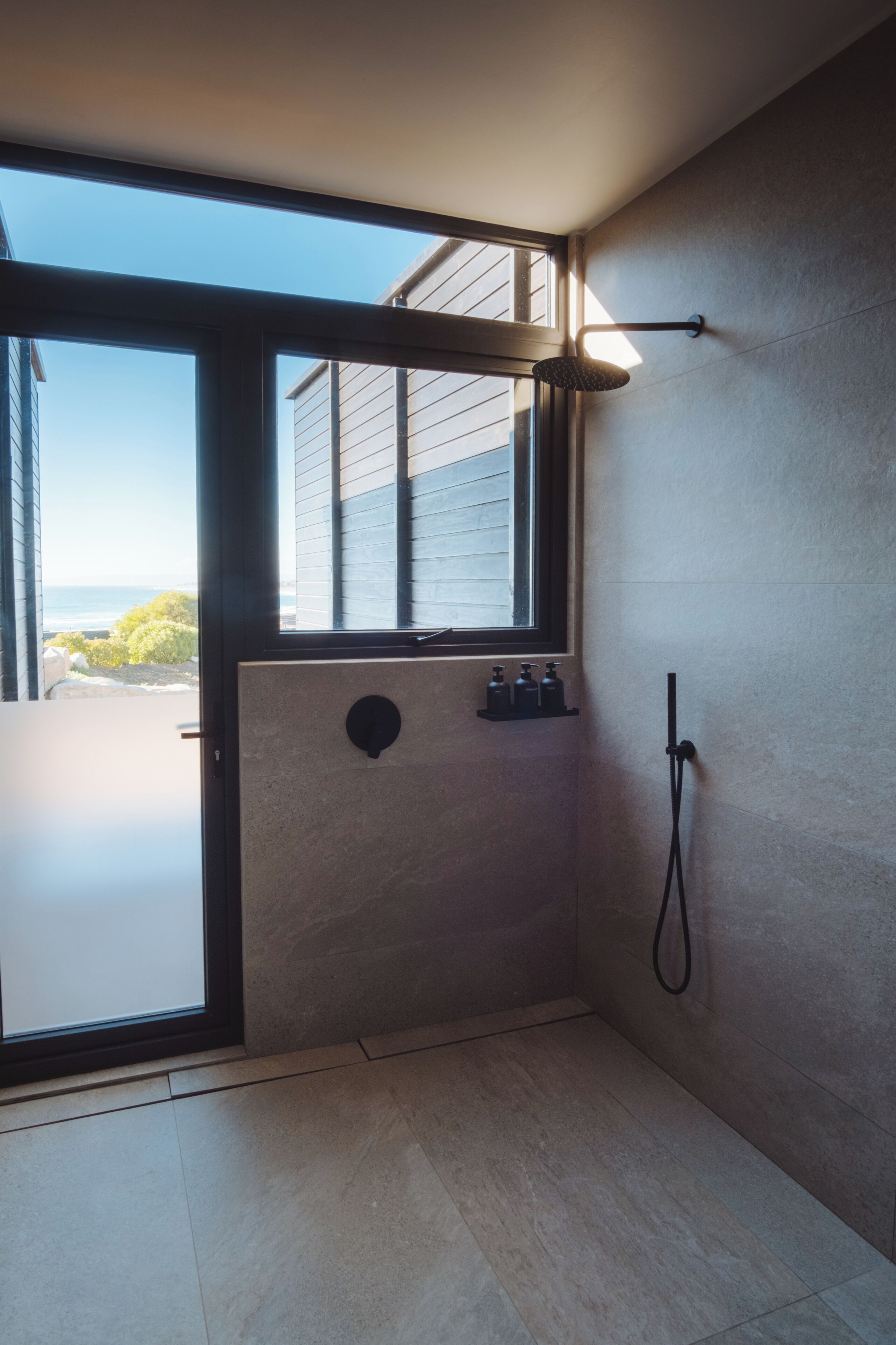 Un baño moderno con un ventanal grande, una ducha y un perchero para toallas.