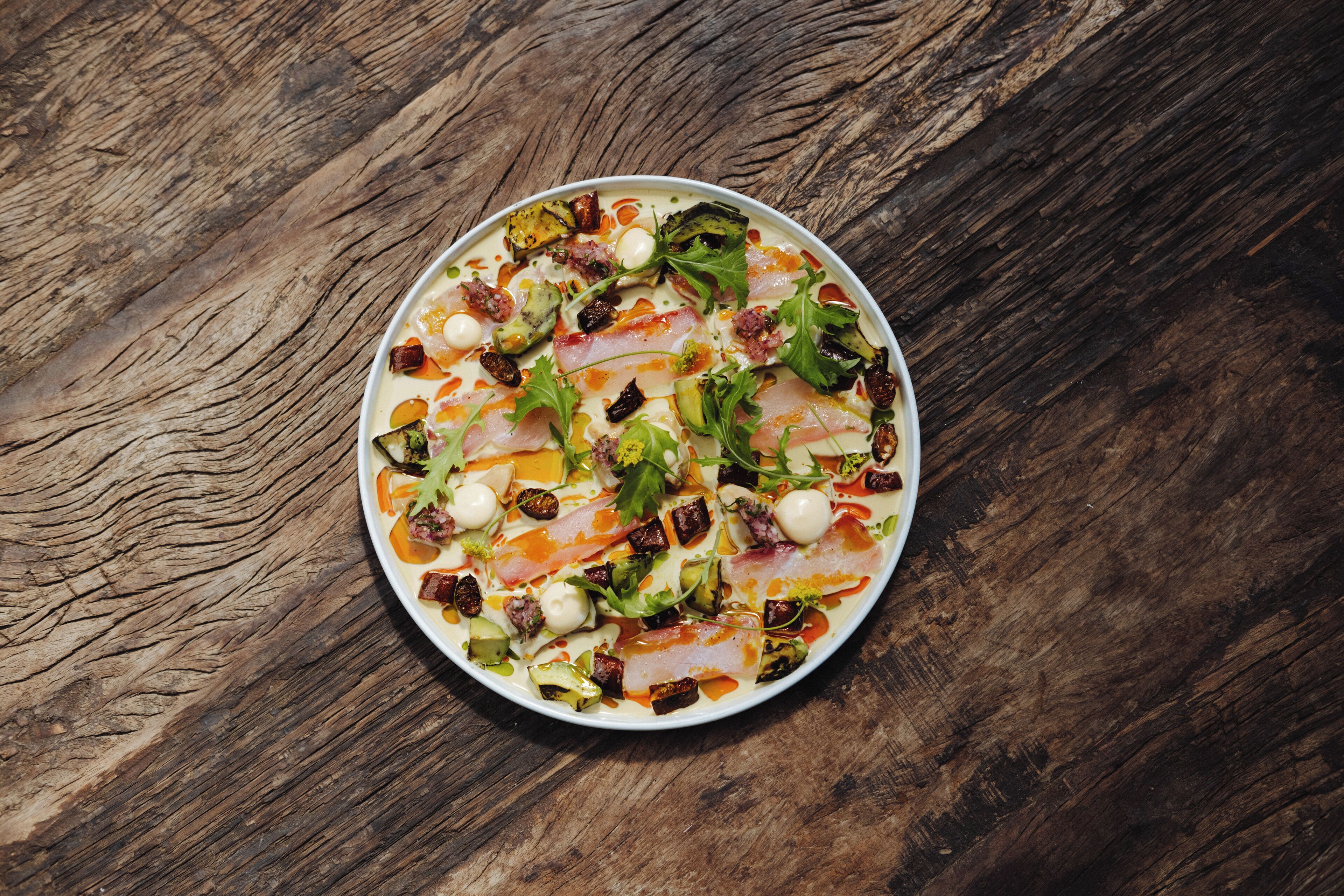 Un plato redondo de comida con varios ingredientes sobre una superficie de madera.