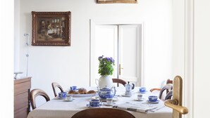 A dining table set with blue and white china, a vase with flowers, and a painting on the wall. - Habitat's Campo di Fiori Apartments (Rome)