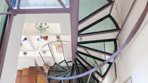 A spiral staircase with glass railings and a metal frame, leading to an upper floor. - Habitat's Campo di Fiori Apartments (Rome)