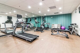 Academia com esteiras, elípticos e bolas de exercício.