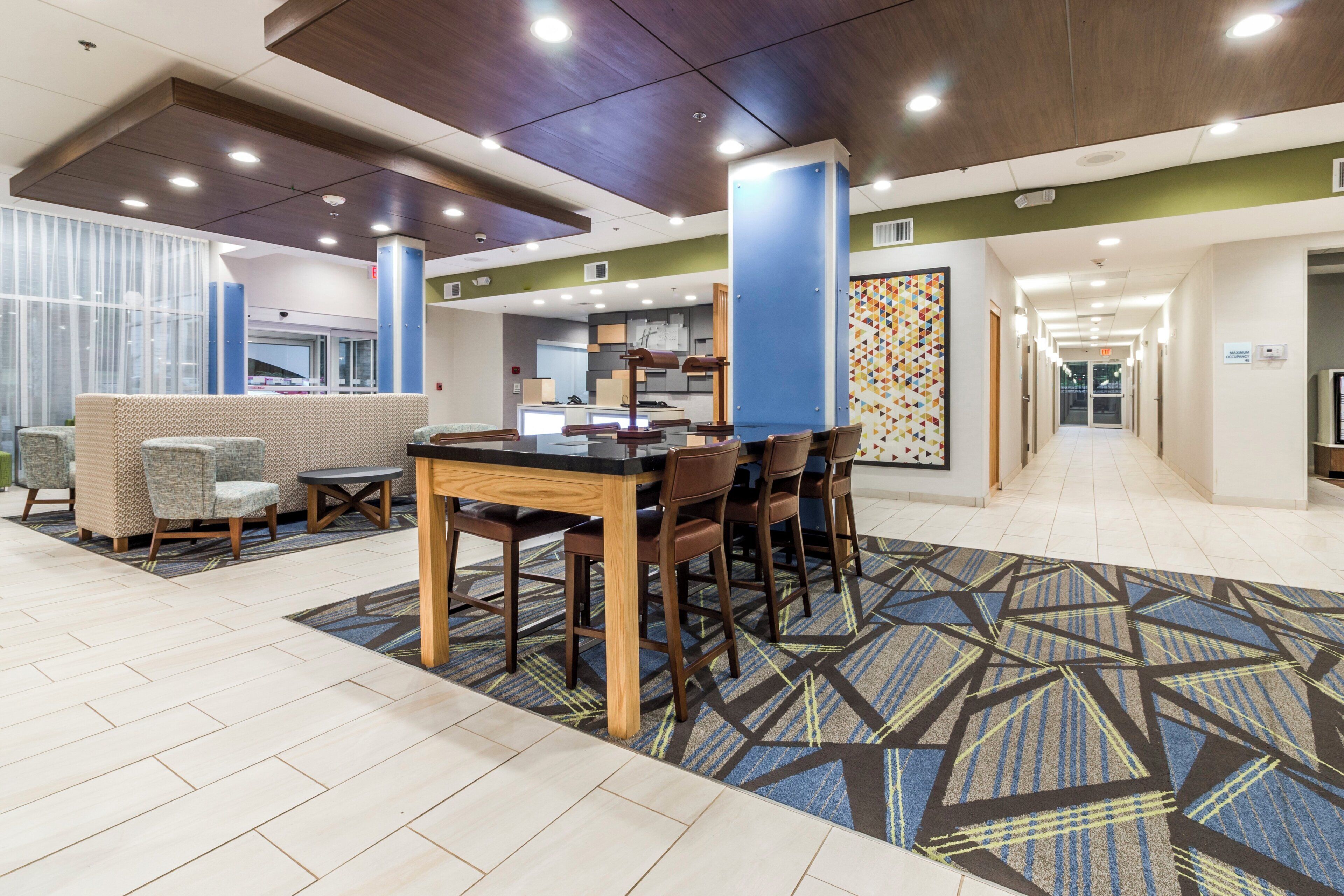 A hotel lobby with a reception desk, seating area, and a patterned carpet.