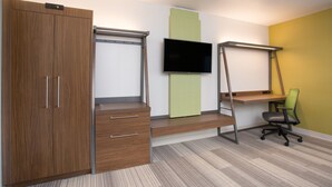 A bedroom with a wooden wardrobe, a desk with a chair, a TV mounted on the wall, and a green accent wall. - Holiday Inn Express Villa Rica by IHG (Villa Rica)